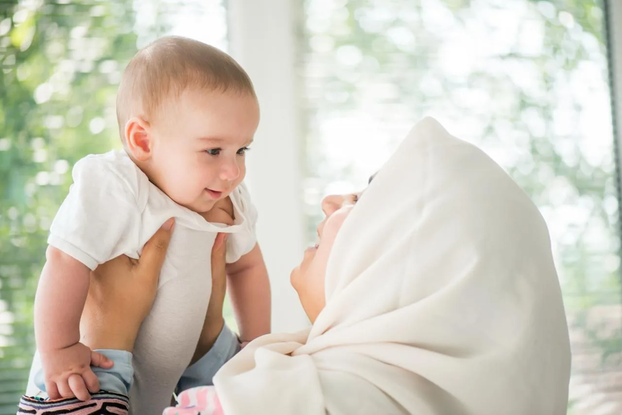 A young child smiling with a parent.
